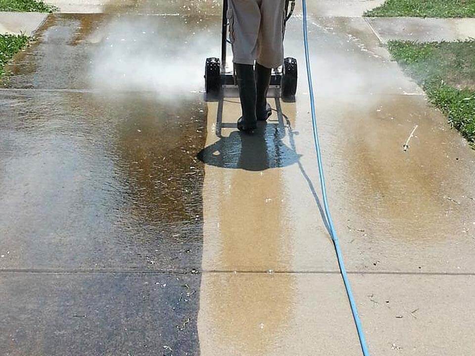 Concrete driveway pressure washing with surface cleaner during cleaning