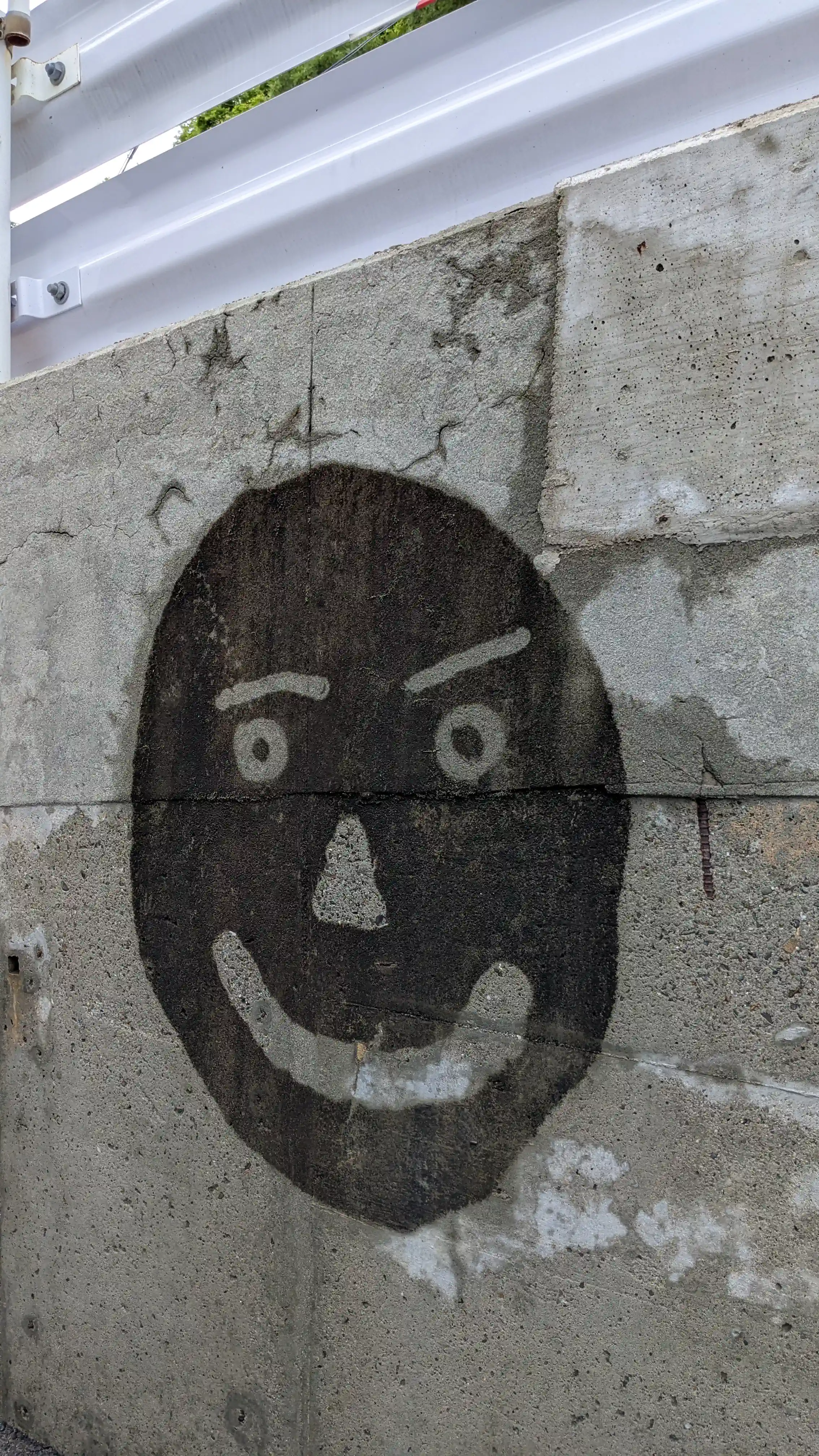 Concrete wall pressure washing test area with uncleaned smiley face mark